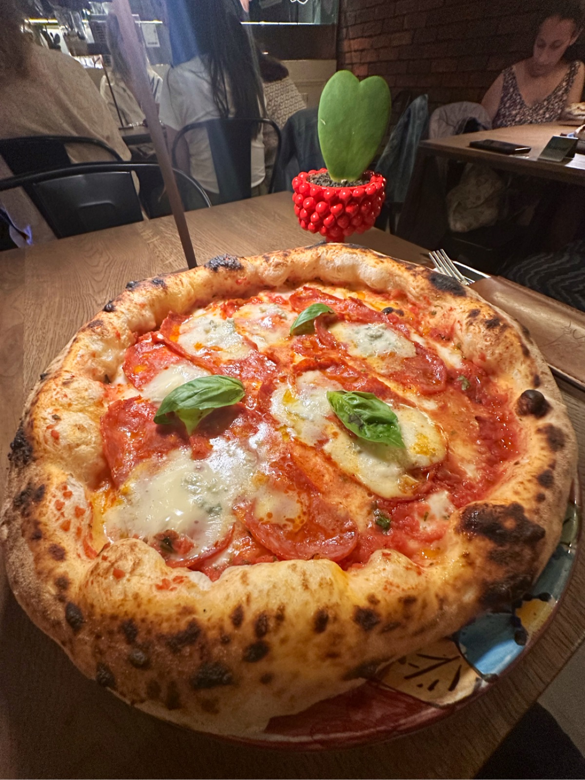 Pizza diavola s bazalkou na drevenom stole